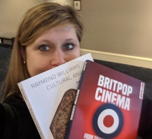 Graduate Student Caucus President Dana Gavin holds up books purchased at the 51st Annual Convention Exhibit Hall in Boston. 